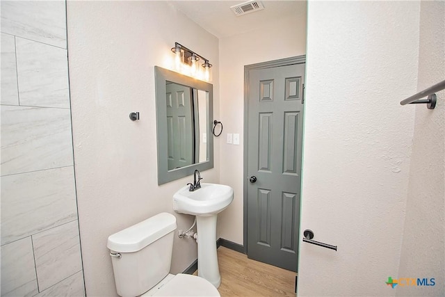 bathroom with hardwood / wood-style floors, toilet, and sink