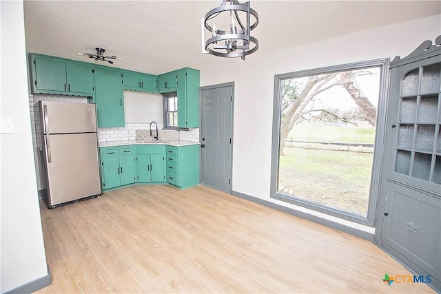 kitchen featuring green cabinets, a healthy amount of sunlight, sink, and stainless steel refrigerator