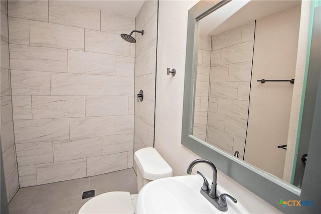 bathroom with sink, toilet, and tiled shower