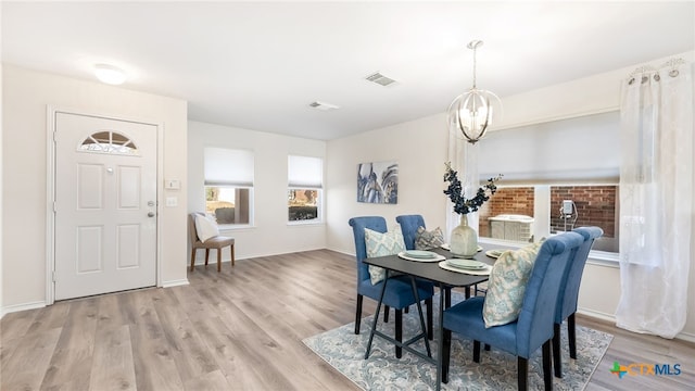 dining room with light wood-type flooring and an inviting chandelier