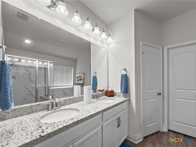 bathroom featuring double vanity, wood finished floors, a sink, and visible vents