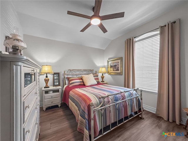 bedroom with vaulted ceiling, dark wood finished floors, a ceiling fan, and baseboards