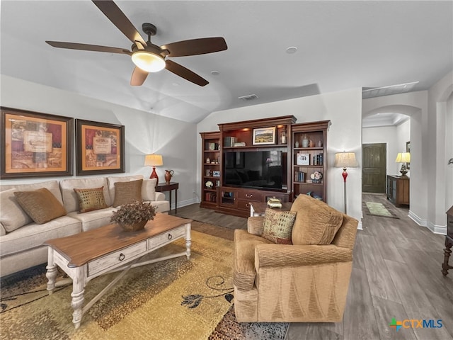 living area featuring arched walkways, wood finished floors, visible vents, and baseboards