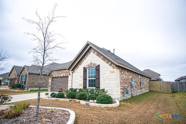 view of home's exterior with a garage, fence, driveway, stone siding, and a lawn