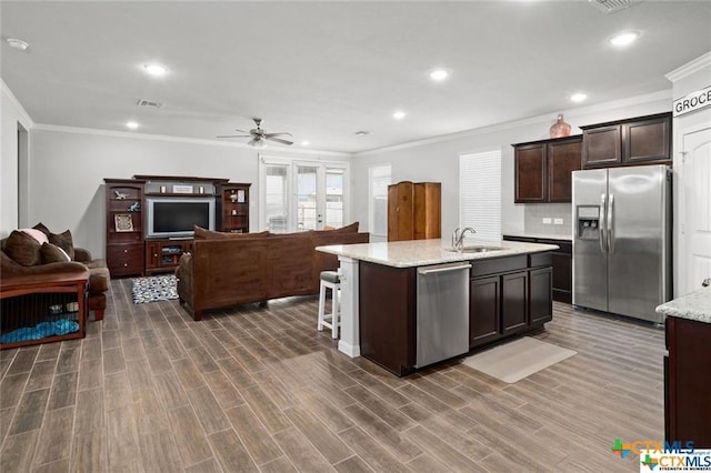 kitchen with appliances with stainless steel finishes, dark hardwood / wood-style floors, sink, dark brown cabinets, and a center island with sink