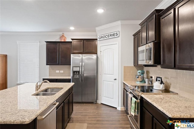 kitchen with sink, crown molding, appliances with stainless steel finishes, dark hardwood / wood-style floors, and an island with sink