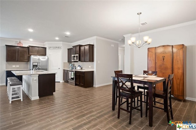 dining room with sink, crown molding, and a chandelier