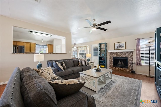 living room with wood finished floors, a healthy amount of sunlight, baseboards, and a tile fireplace