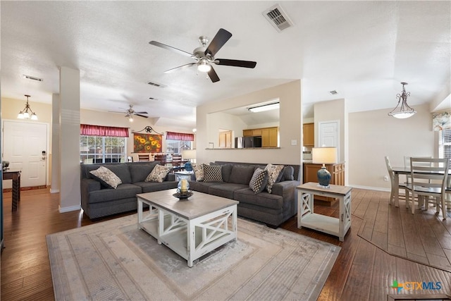 living area featuring visible vents, a ceiling fan, baseboards, and hardwood / wood-style floors