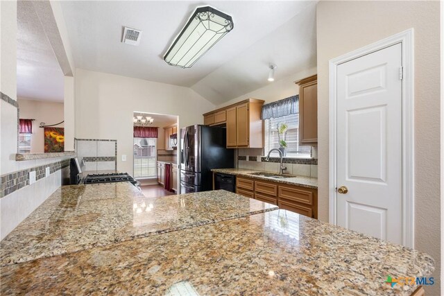 kitchen with visible vents, backsplash, dishwasher, freestanding refrigerator, and a sink