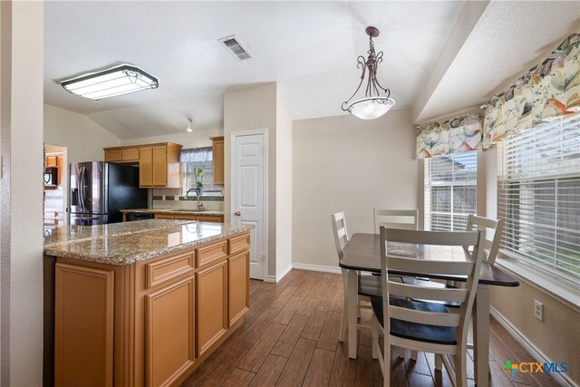 kitchen with visible vents, a sink, vaulted ceiling, stainless steel fridge, and dark wood-style flooring