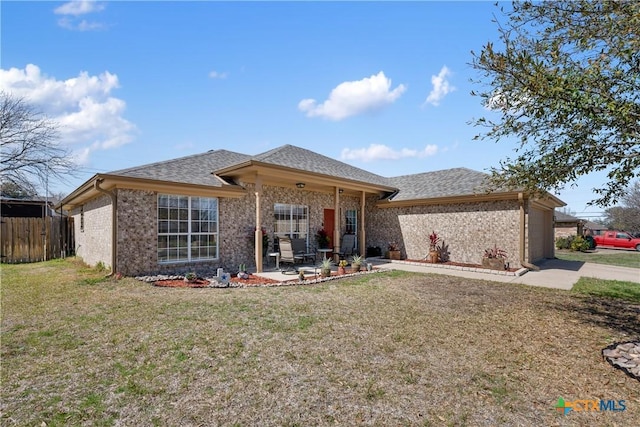 back of house featuring a patio, fence, a yard, a garage, and brick siding