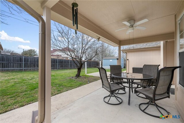 view of patio / terrace with outdoor dining space, a fenced backyard, a shed, an outdoor structure, and ceiling fan