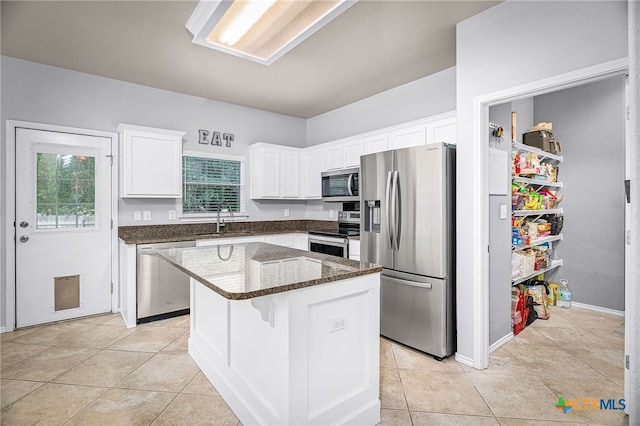 kitchen featuring a sink, dark stone countertops, white cabinets, a kitchen island, and appliances with stainless steel finishes