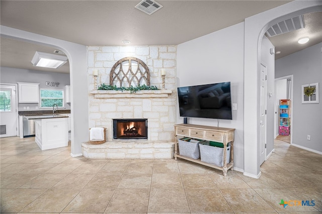 living room featuring light tile patterned floors, visible vents, a fireplace, and arched walkways