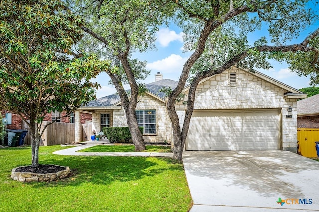 ranch-style house featuring an attached garage, driveway, a front lawn, and stone siding