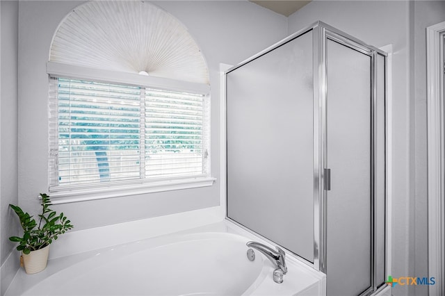 full bathroom featuring a shower stall, a wealth of natural light, and a garden tub