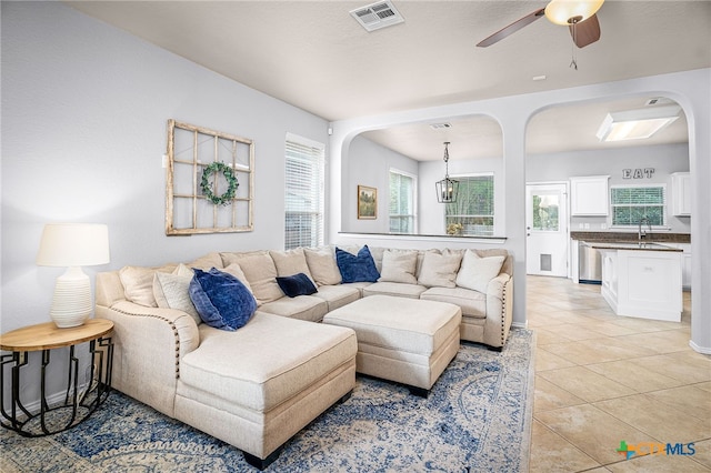 living area with light tile patterned floors, ceiling fan, visible vents, and arched walkways