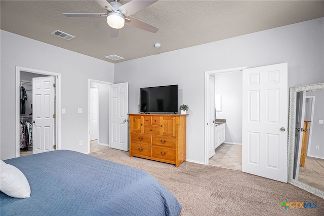 bedroom featuring ensuite bathroom, visible vents, a spacious closet, and light carpet
