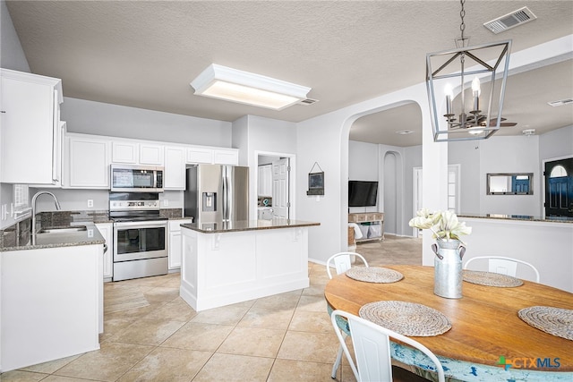 kitchen featuring a sink, visible vents, a center island, light tile patterned floors, and appliances with stainless steel finishes