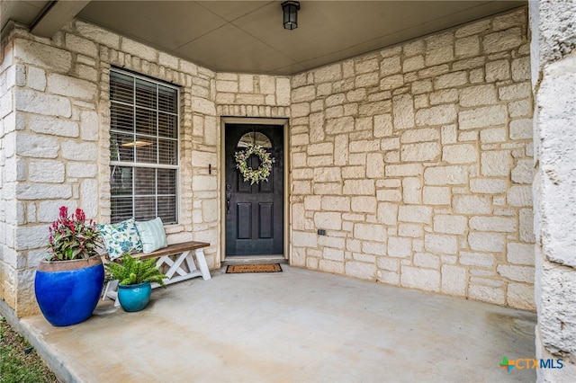 doorway to property featuring covered porch and stone siding