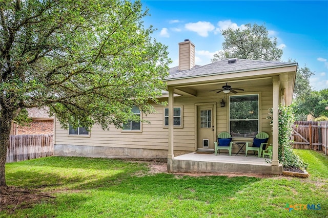 back of house with a chimney, fence private yard, a lawn, and ceiling fan