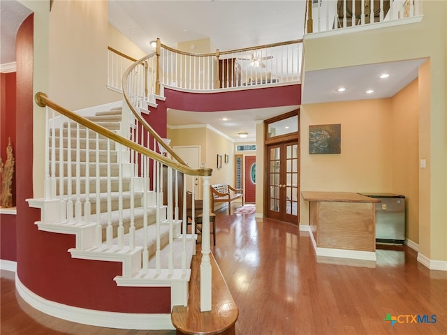 foyer with a high ceiling, french doors, crown molding, and wood-type flooring