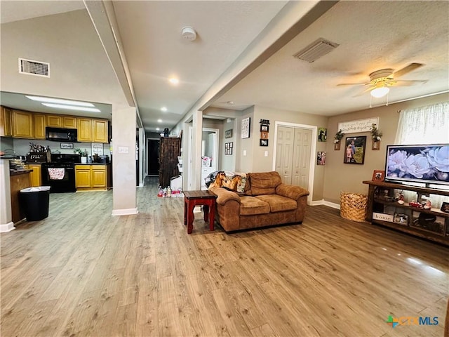 living room featuring light wood-type flooring, ceiling fan, and a barn door