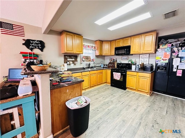 kitchen with kitchen peninsula, sink, black appliances, and light hardwood / wood-style floors