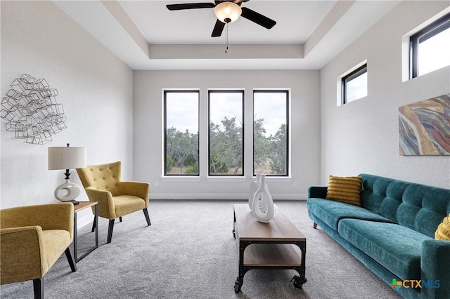 carpeted living room featuring a tray ceiling and ceiling fan