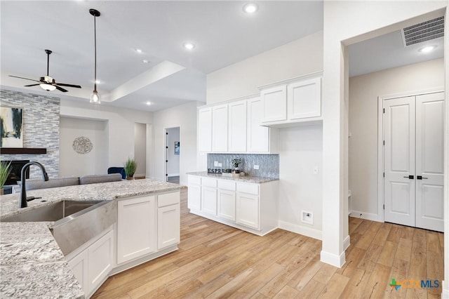 kitchen featuring sink, white cabinets, light stone counters, and light hardwood / wood-style floors