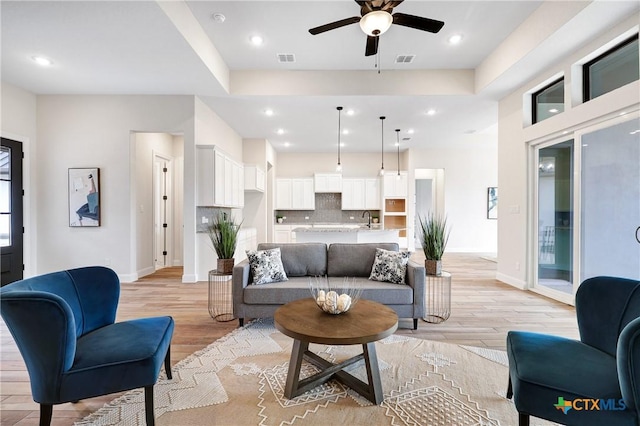 living room featuring sink, ceiling fan, and light hardwood / wood-style flooring