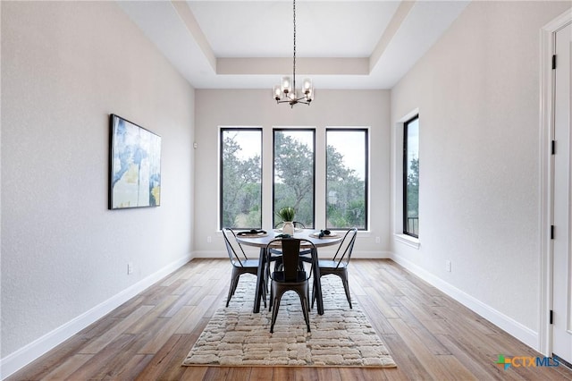 dining area featuring a tray ceiling, light hardwood / wood-style flooring, and a notable chandelier