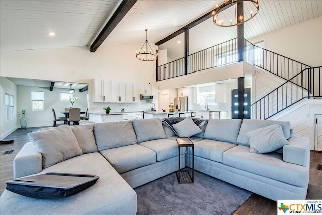 living room with sink, dark wood-type flooring, beamed ceiling, a notable chandelier, and plenty of natural light