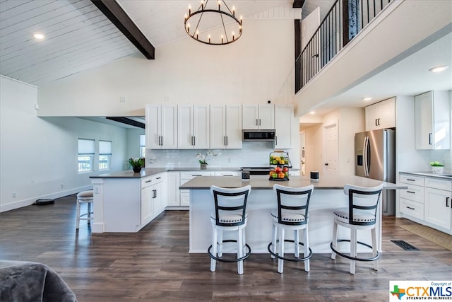 kitchen with a kitchen bar, pendant lighting, beam ceiling, white cabinets, and a kitchen island