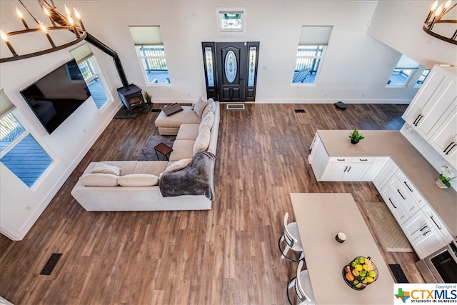 living room with a wood stove, a towering ceiling, dark hardwood / wood-style floors, and an inviting chandelier