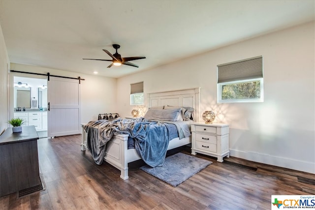 bedroom with a barn door, ceiling fan, and dark hardwood / wood-style flooring