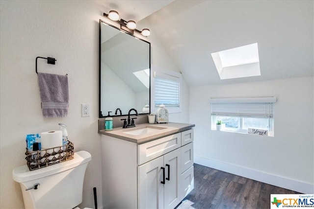 bathroom featuring hardwood / wood-style floors, vanity, toilet, and vaulted ceiling with skylight