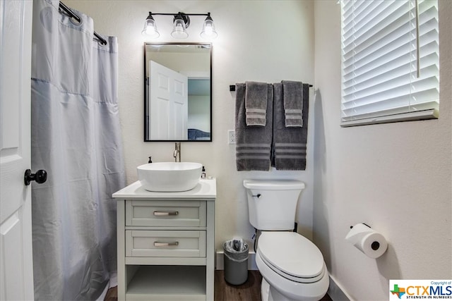 bathroom with curtained shower, vanity, and toilet