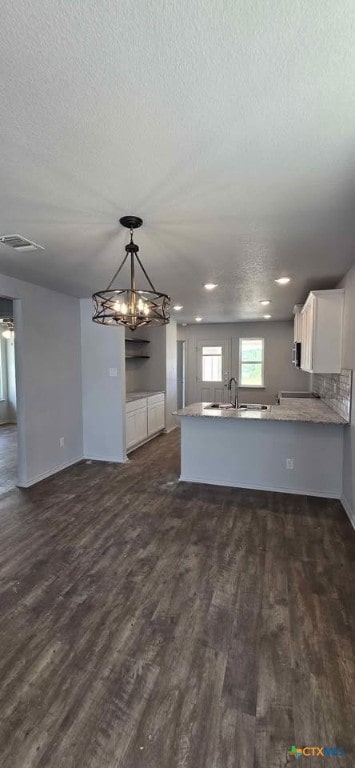 313 Monty Ave, Copperas Cove, TX 76522 - kitchen with a textured ceiling, dark wood-style flooring, open floor plan, white cabinets, and a peninsula