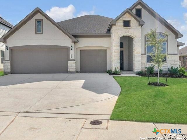 french country home featuring a garage and a front lawn