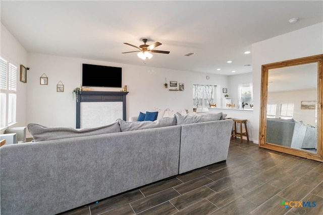 living room featuring a wealth of natural light, ceiling fan, and dark hardwood / wood-style flooring