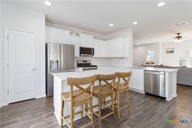 kitchen with white cabinetry, appliances with stainless steel finishes, dark wood-type flooring, kitchen peninsula, and ceiling fan