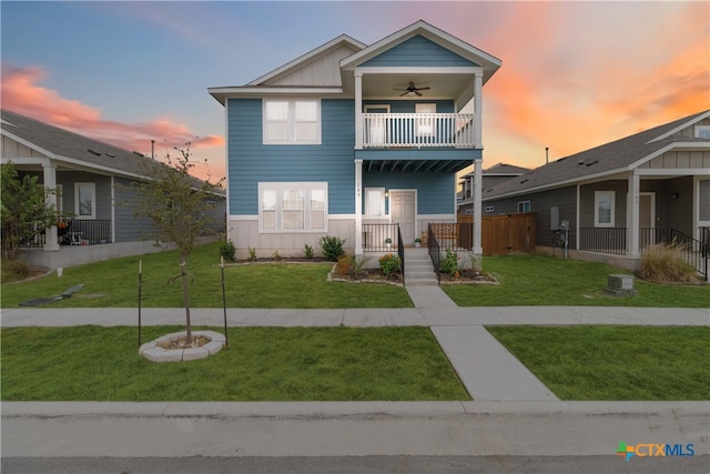 view of front of property with ceiling fan, a balcony, and a yard