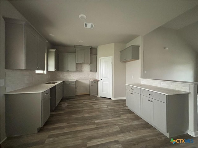 kitchen with visible vents, dark wood-style flooring, a sink, gray cabinetry, and backsplash