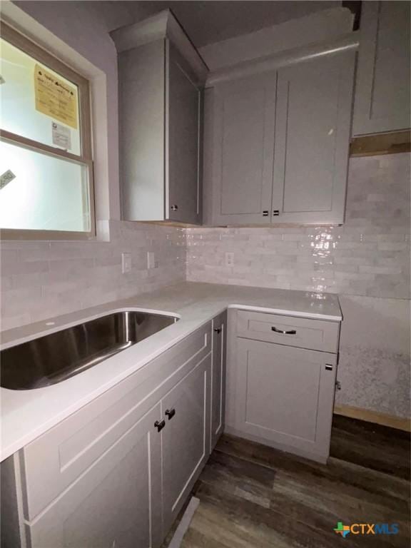 kitchen featuring tasteful backsplash, a sink, light countertops, and dark wood finished floors