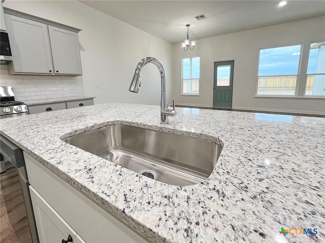 kitchen featuring gas range, light stone countertops, and sink