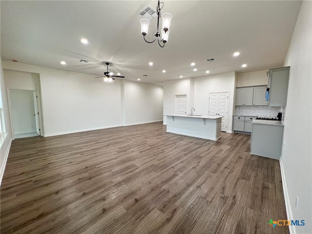 unfurnished living room featuring hardwood / wood-style flooring, sink, and ceiling fan with notable chandelier