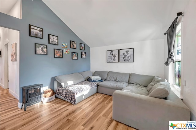 living room featuring a wood stove, a wealth of natural light, lofted ceiling, and light hardwood / wood-style floors