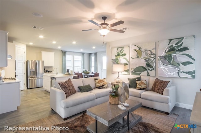 living room with ceiling fan, sink, and light hardwood / wood-style floors